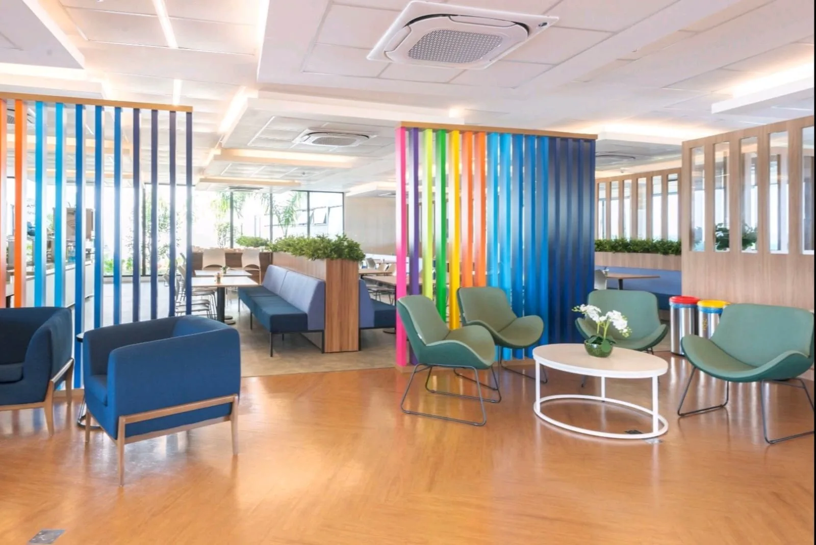 Ambiente corporativo com mesas, áreas de convivência e divisórias coloridas